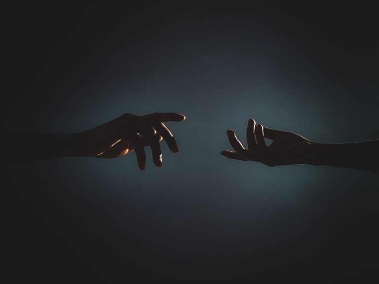 Silhouettes de mains se rejoignant dans l'obscurité