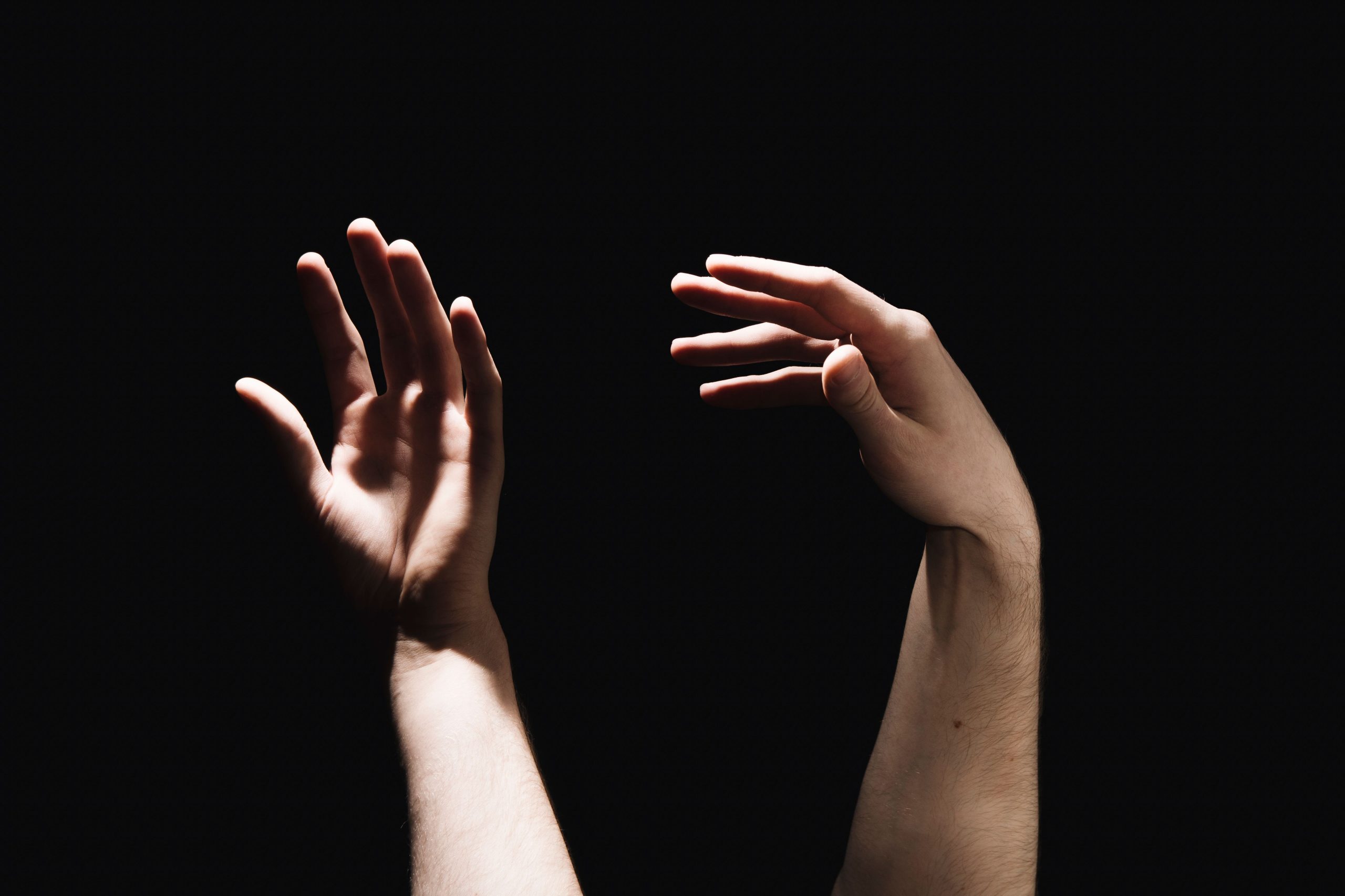Mains levées vers le haut sur fond noir dramatique