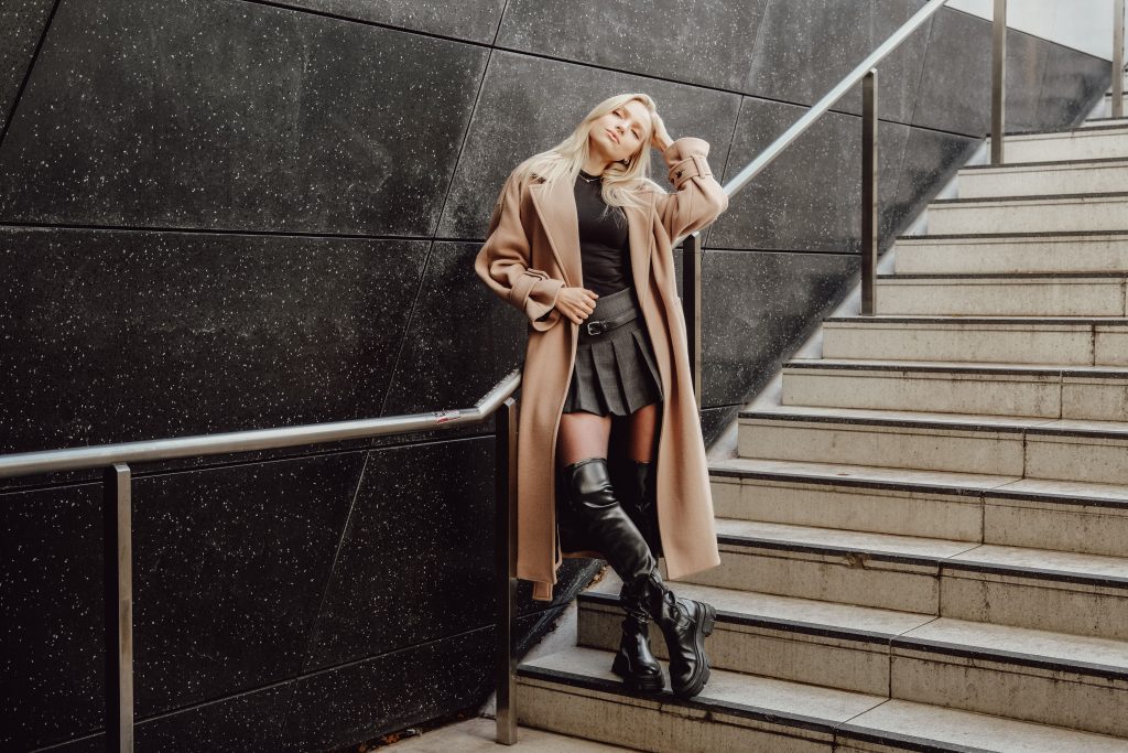 Femme élégante en bottes hautes sur des marches urbaines