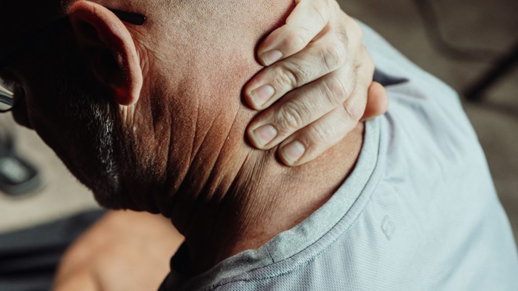 Homme tenant son cou avec une douleur visible