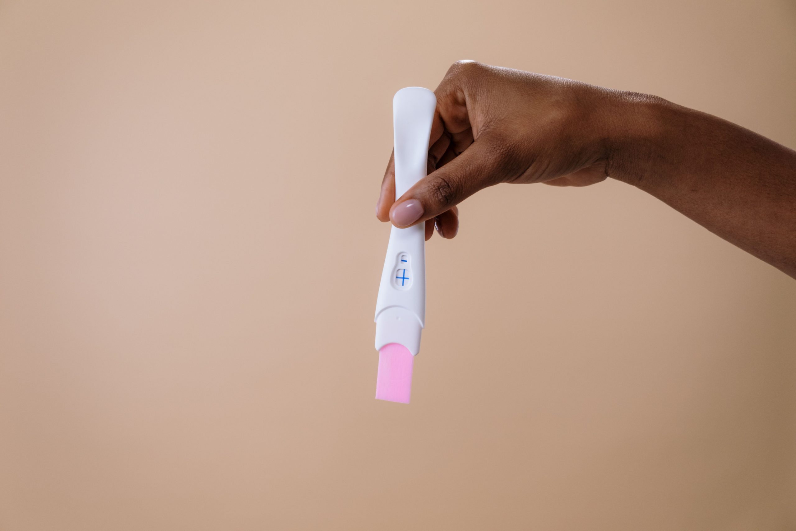 Main de femme tenant un test de grossesse positif